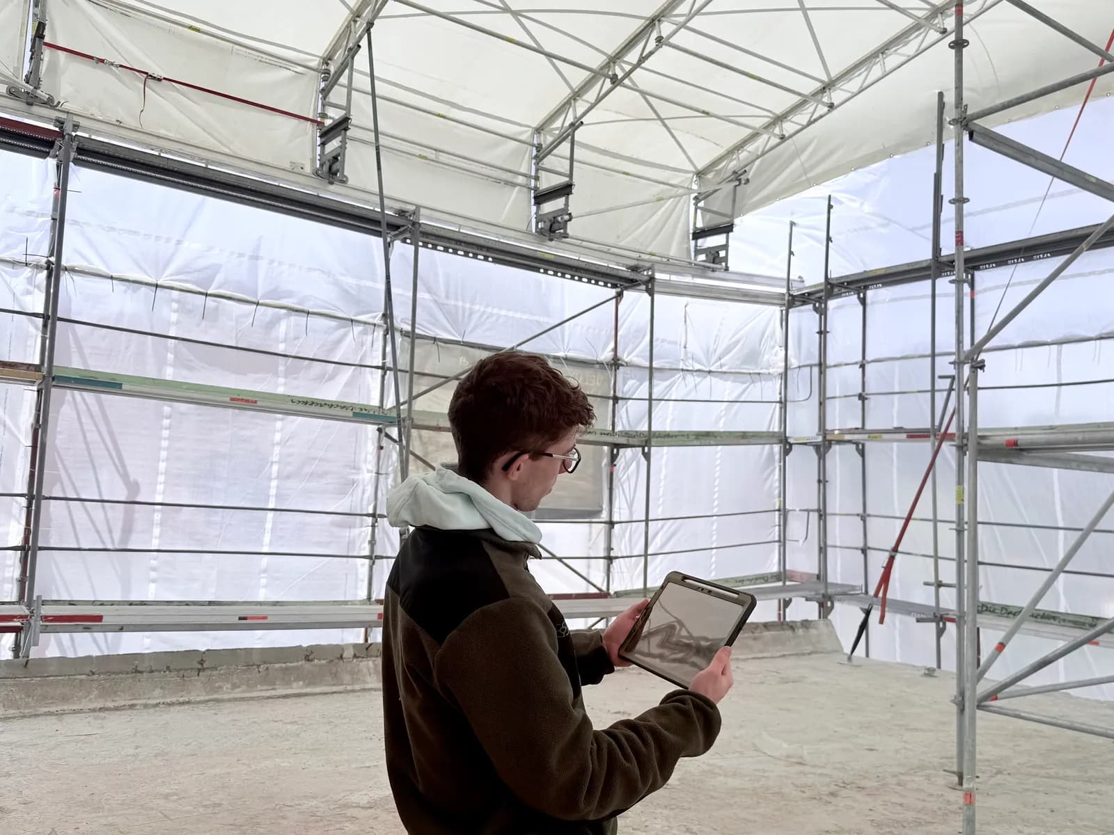 Bauleiter dokumentiert den Baufortschritt vor Ort per Tablet mit der PixService App auf einer eingerüsteten Baustelle